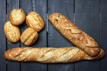 Different kinds of bread rolls on black board from above. Kitchen or bakery poster design.