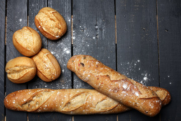 Different kinds of bread rolls on black board from above. Kitchen or bakery poster design.