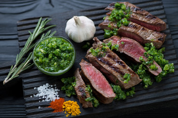Sliced barbecued rump steak with chimichurri sauce, close-up