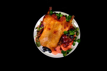 Roast duck with fruit on black background