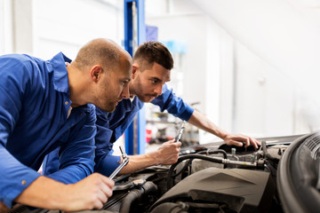 Fototapeta na wymiar mechanic men with wrench repairing car at workshop