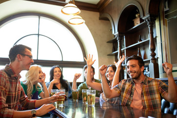 friends with beer watching football at bar or pub