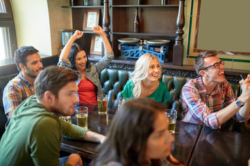 friends with beer watching football at bar or pub