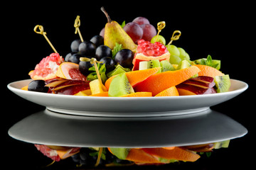 Delicious fruit plate on black background