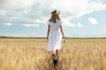 happy young woman in flower wreath on cereal field