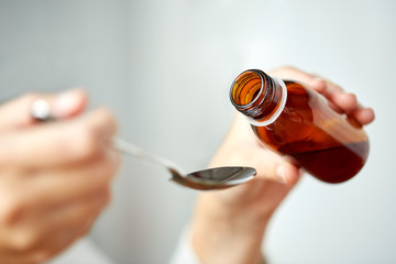 woman pouring medication from bottle to spoon