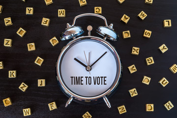 Time to vote - Alarm clock on wooden table with letters