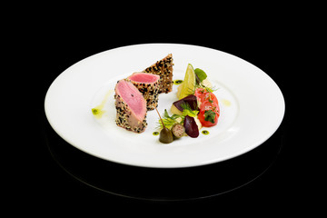 Tuna steak with vegetables on black background