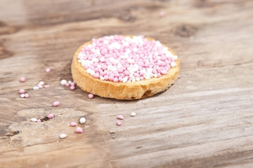 Traditional Dutch birth celebration biscuit with pink muisjes on wooden background