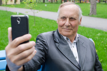 Aged man is using cellphone in the park