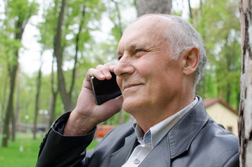 Aged man is using cellphone in the park