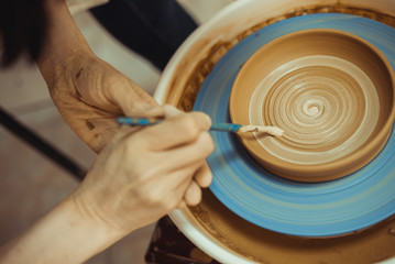 man paints a clay plate