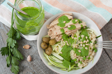 vegan zucchini pasta with tofu, bulgur, green peas, olives and pesto of parsley in a jar. vegetables every day for your health!