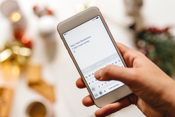 Hand holding a smartphone and writting new year resolutions