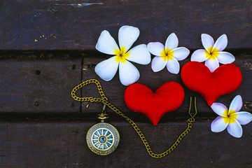 Red heart on the floor wood and Antique clock or Frangipani flowers time and love concept