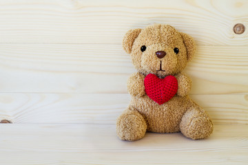 Teddy bear holding a heart-shaped pillow
