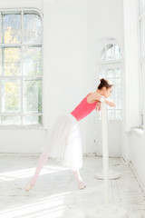 Ballerina posing in pointe shoes at white wooden pavilion