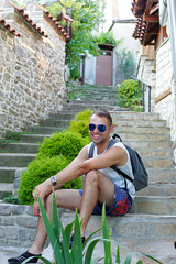 Wonderful guy sitting on the stairs and smiling at the camera