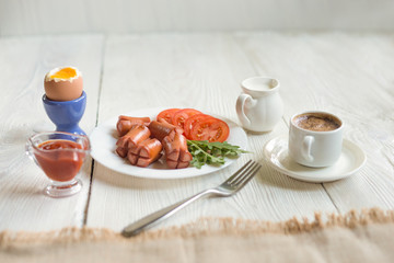 Breakfast - boiled egg, fried sausages, coffee cup and vegetable