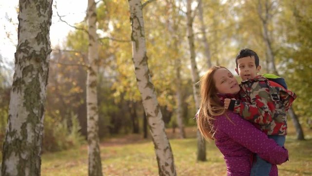 Young boy embracing and kissing his mother,outdoors in autumn