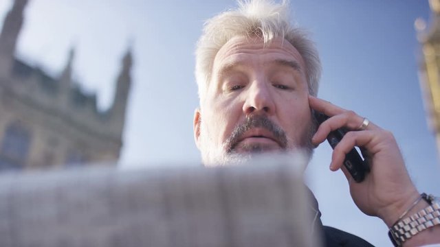 4K Mature investor finishes a call with his broker, in slow motion