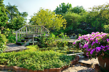  The garden has a pathway and a wooden bridge surrounded by trees.