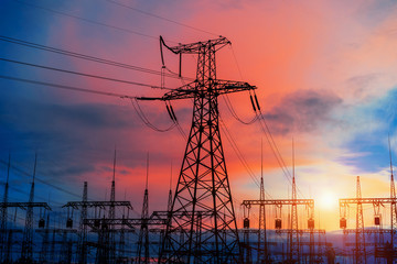 Electrical pylons on the background of the transformer substation during sunset