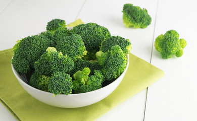 Raw broccoli in bowl on white table