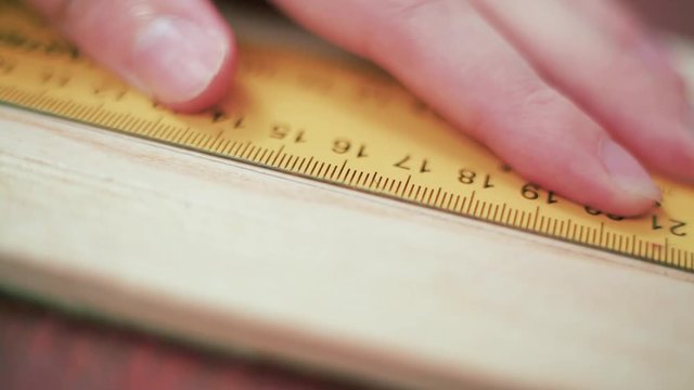 Close up view of a man's hands measuring wooden plank with tape line