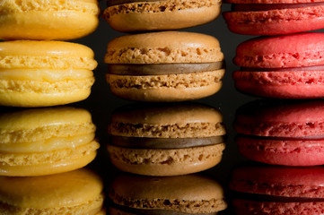 Stacks of multicolored macaroon isolated on black background with reflection