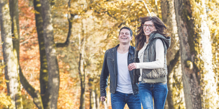 Junges P&auml;rchen l&auml;uft lachend im herbstlichen Park