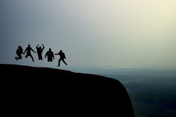 silhouette group of young jumping on the top of the mountain, copy space, sunlight