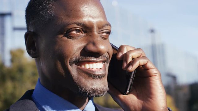 4K African american business man in the city on his phone cheerfully, in slow motion