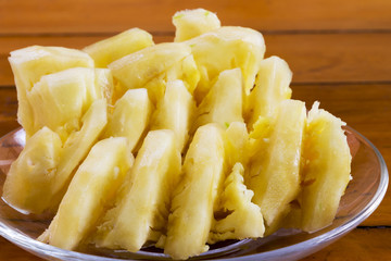 Pineapple slices in a glass plate placed on a wooden table.