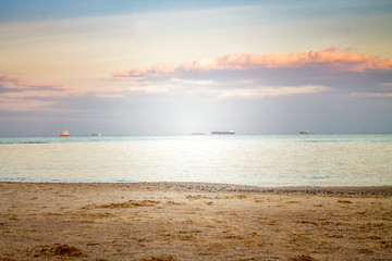 Seascape view from shore during sunset. Ships  are on horizont