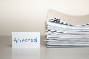 Accepted; Stack of Documents on white desk and Background.