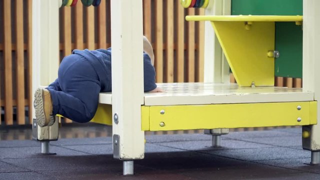 A little boy trying to climb in house on the playground.