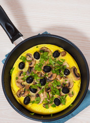 omelet with mushrooms, and olives in a frying pan