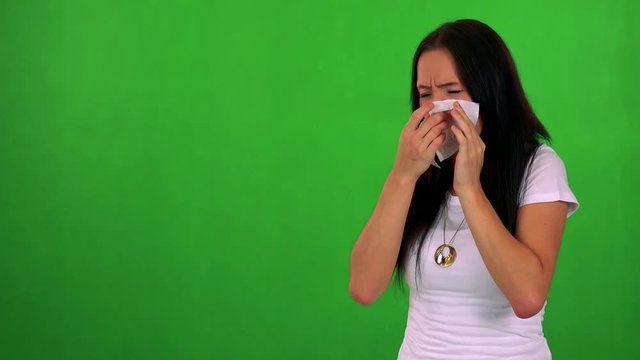 young pretty woman blow one's nose - green screen - studio 