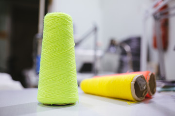 Green, yellow, red bobbin of thread on table