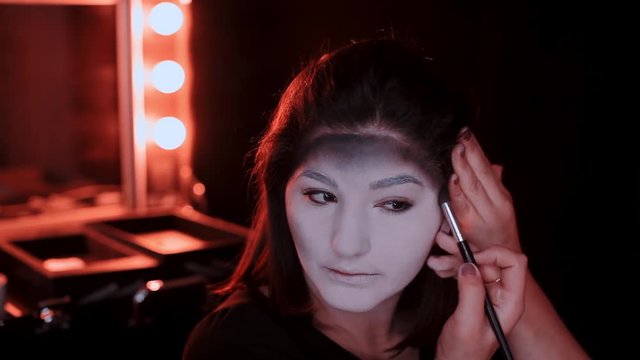 girl makes a make-up in the style of a witch Halloween
