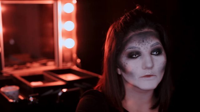 girl makes a make-up in the style of a witch Halloween