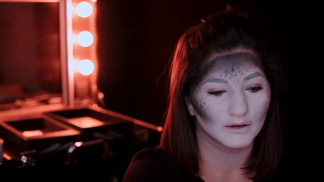 girl makes a make-up in the style of a witch Halloween