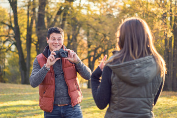 Young Man photographing his Girlfriend in the Park