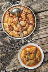Plateful Of Cabbage Rolls Stuffed With Minced Meat Cooked In Tomato Sauce In Stainless Steel Saucepot Set On Old Wooden Garden Table