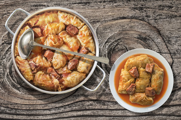 Plateful Of Cabbage Rolls Stuffed With Minced Meat Cooked In Tomato Sauce In Stainless Steel Saucepot Set On Old Wooden Garden Table