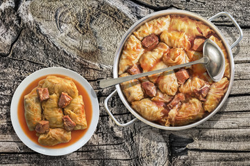 Plateful Of Cabbage Rolls Stuffed With Minced Meat Cooked In Tomato Sauce In Stainless Steel Saucepot Set On Old Wooden Garden Table
