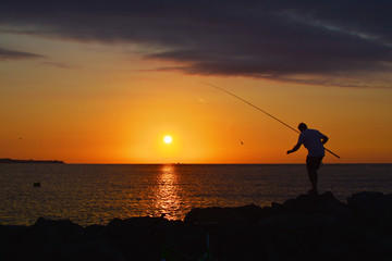 Silhouette of fisherman by the sea on sunrise 
