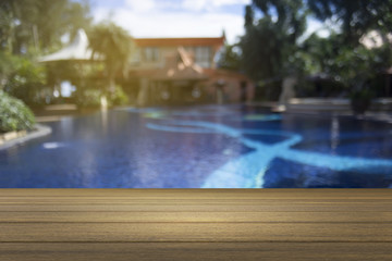 Wooden board empty table against of blurred swimming pool background. Perspective brown wood over swiming pool can be used for display or present your products.Mock up your products