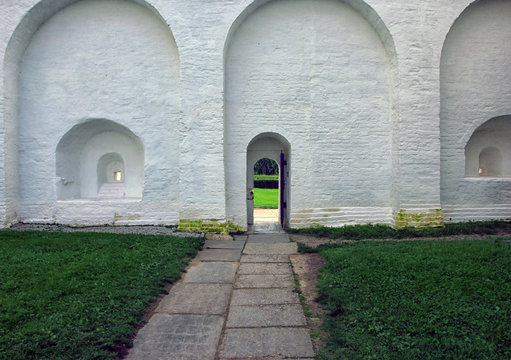 a small arched door in the large white stone wall